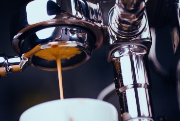 Espresso machine extracting coffee and dripping in white cup
