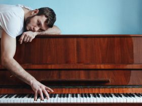 Melancholic pianist playing piano near blue wall