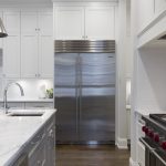Stainless steel refrigerator beside white kitchen cabinet