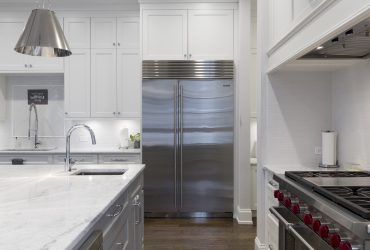 Stainless steel refrigerator beside white kitchen cabinet
