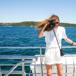 Woman capturing photo while holding hand rails on boat
