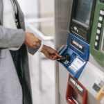 Faceless woman inserting credit card into subway ticket machine