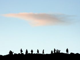 Silhouette of people standing on rock